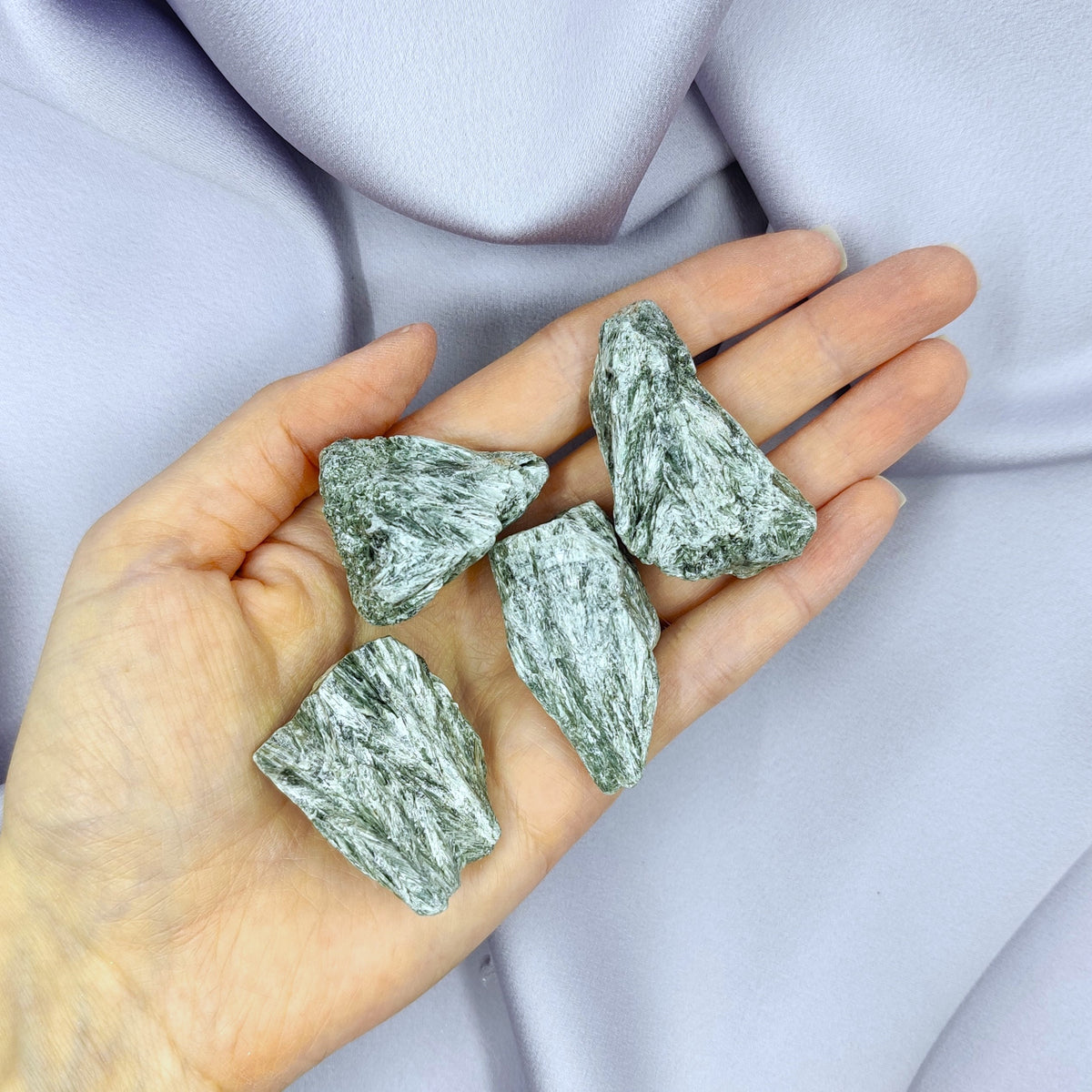Silvery seraphinite raw pieces in hand