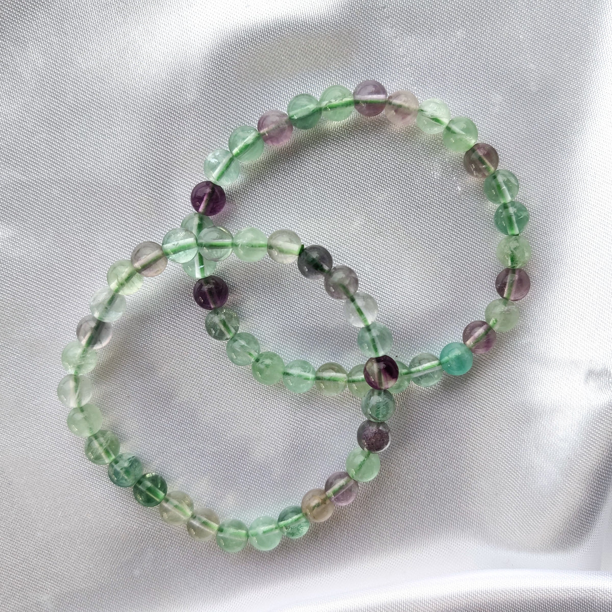 Transparent fluorite bead bracelets on white silk fabric