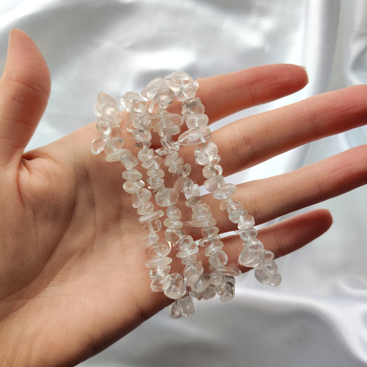 Clear Quartz chip bracelets around a hand on a white background