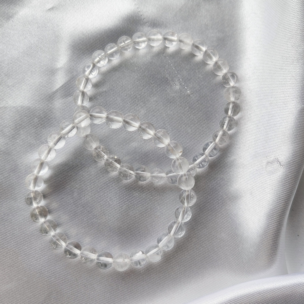 Bright rock crystal pearl bracelets on white silk fabric