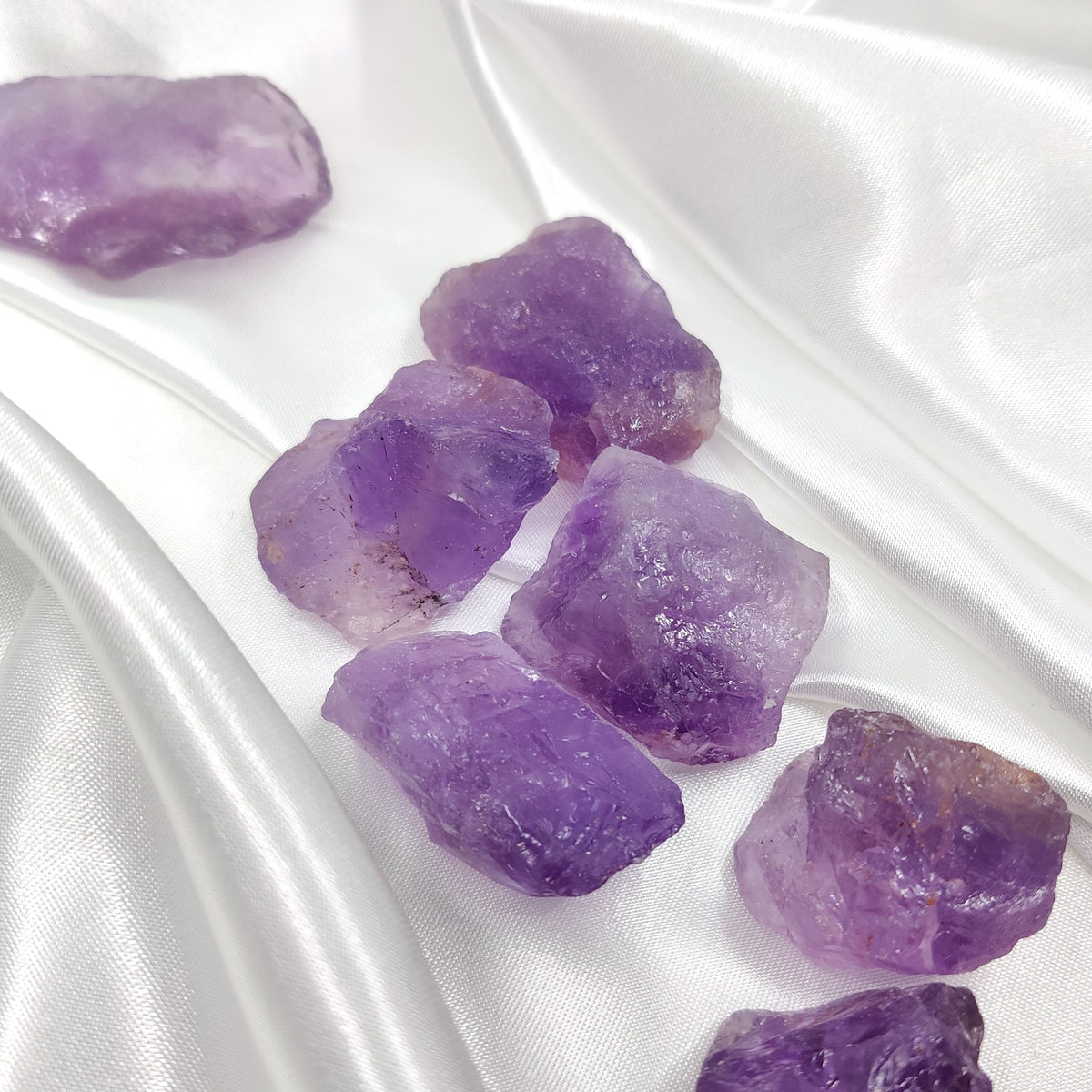 Purple rough amethyst stones on white silk fabric