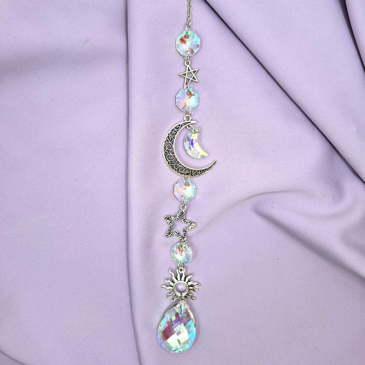 A light-emitting crescent moon sun catcher photographed against a purple background