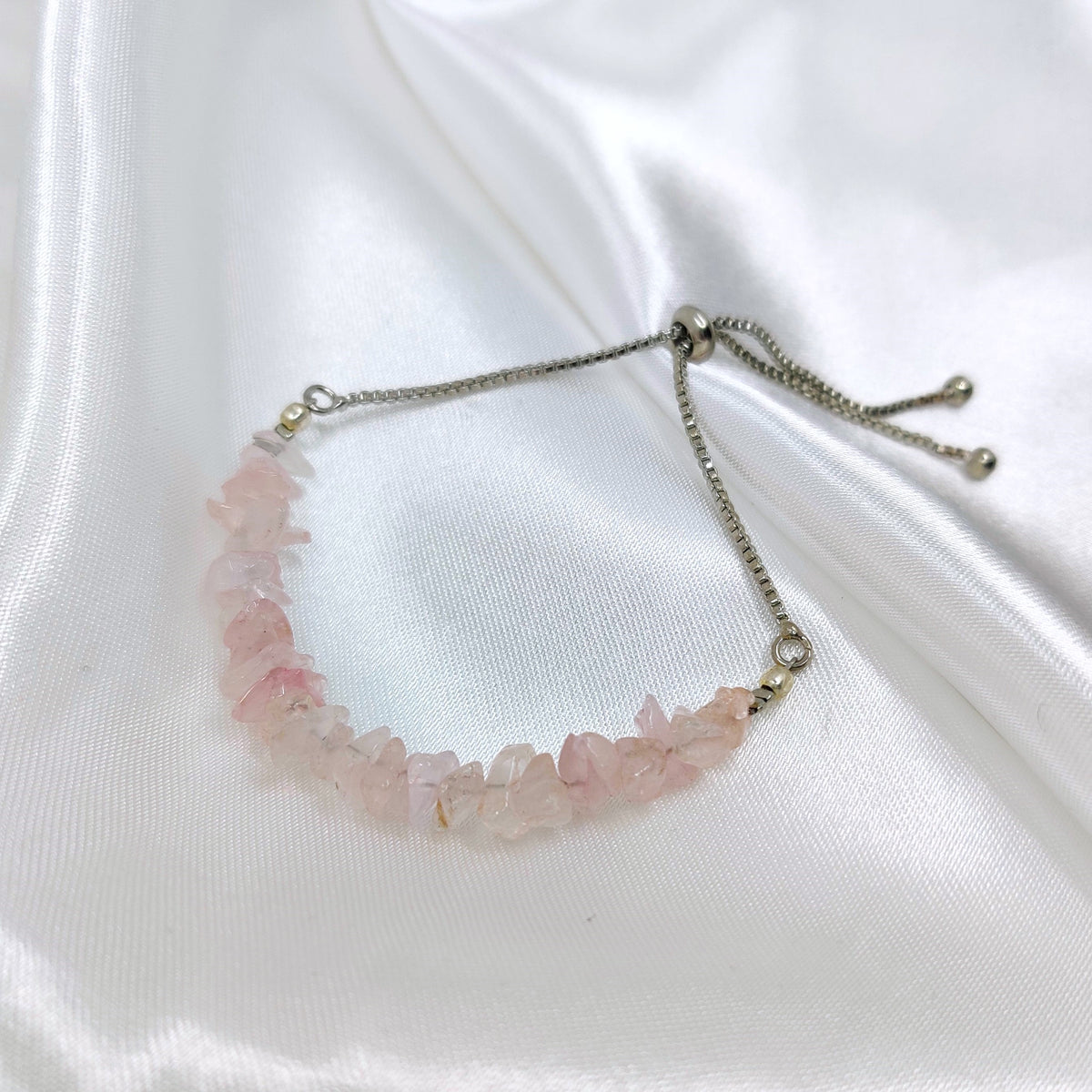 Adjustable rose quartz bracelet with a chain on a white background