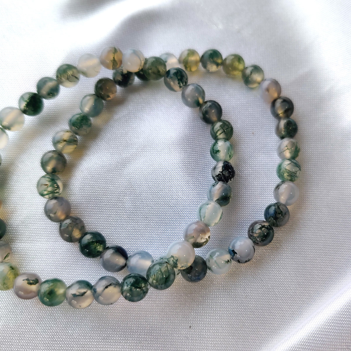 Green moss agate bead bracelets on white silk fabric
