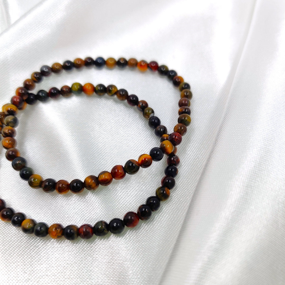 Dark-colored tiger’s eye pearl bracelets on a white background