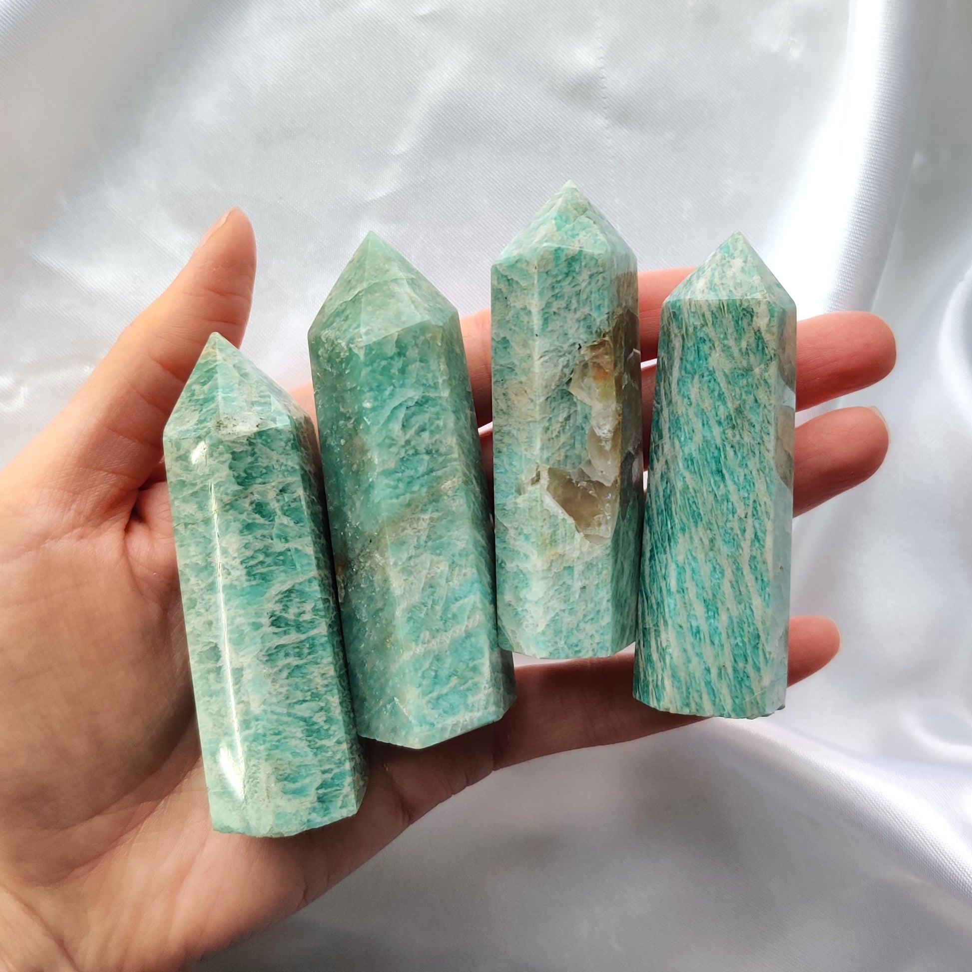 Sinivihreät amatsoniittitornit kädessä kuvattuna valkoisella taustalla