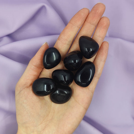 Mustat rumpuhiotut obsidiaanit kädessä kuvattuna
