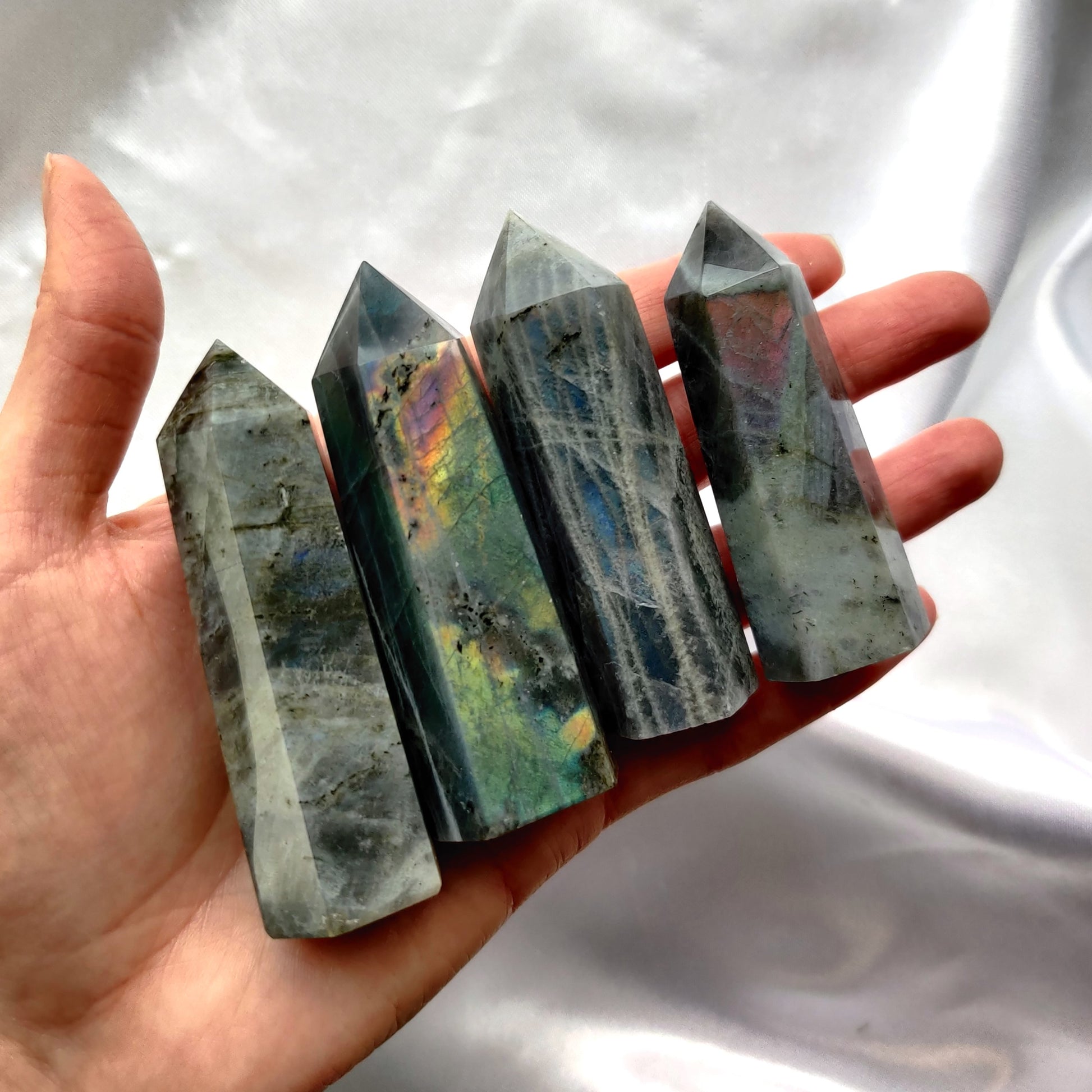 Säihkyvät labradoriitti kivitornit kädessä valkoisella taustalla