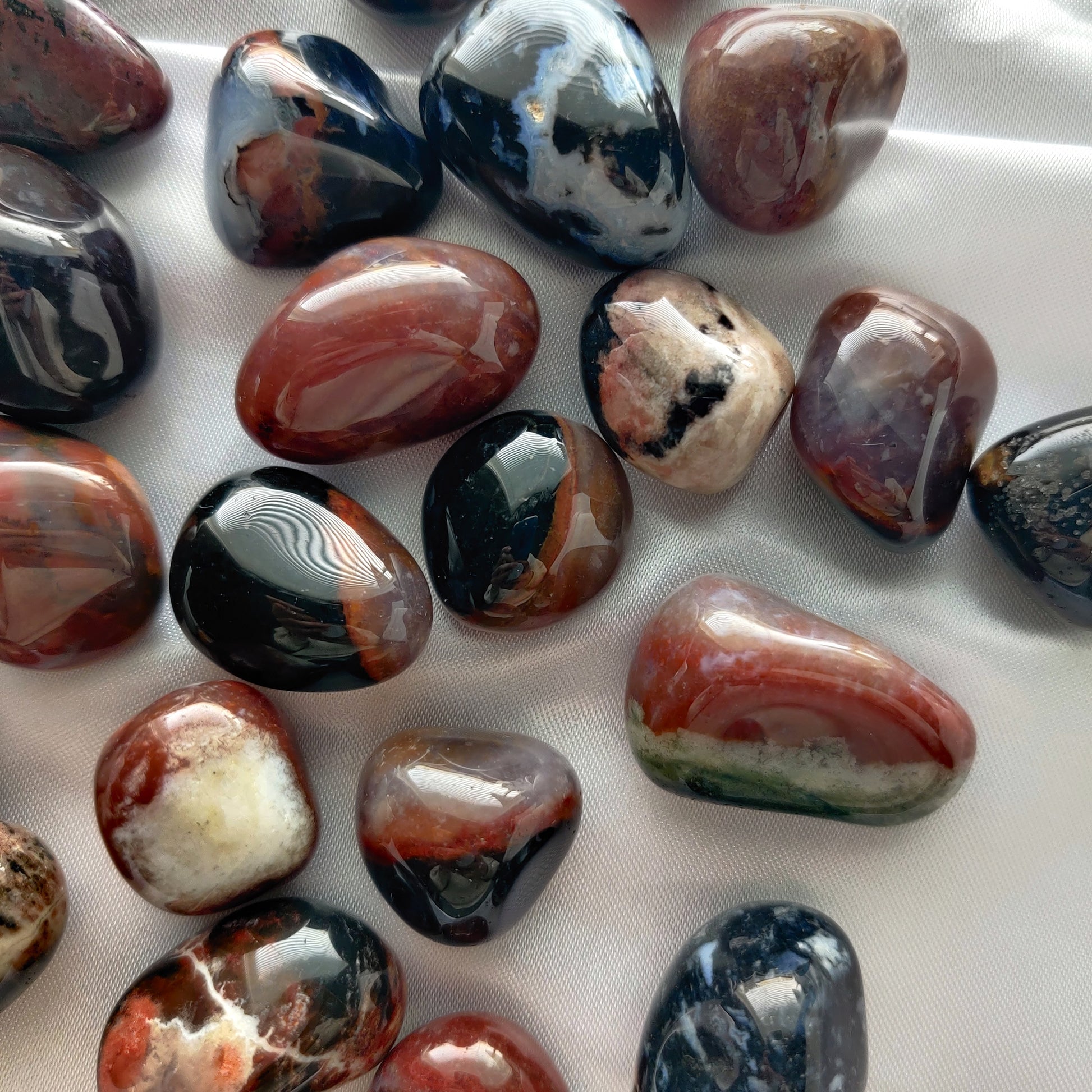 Rumpuhiottuja värikkäitä sardonyx kiviä valkoisella taustalla
