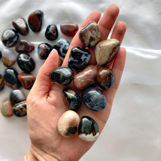 Värikkäät rumpuhiotut sardonyx kivet kädessä