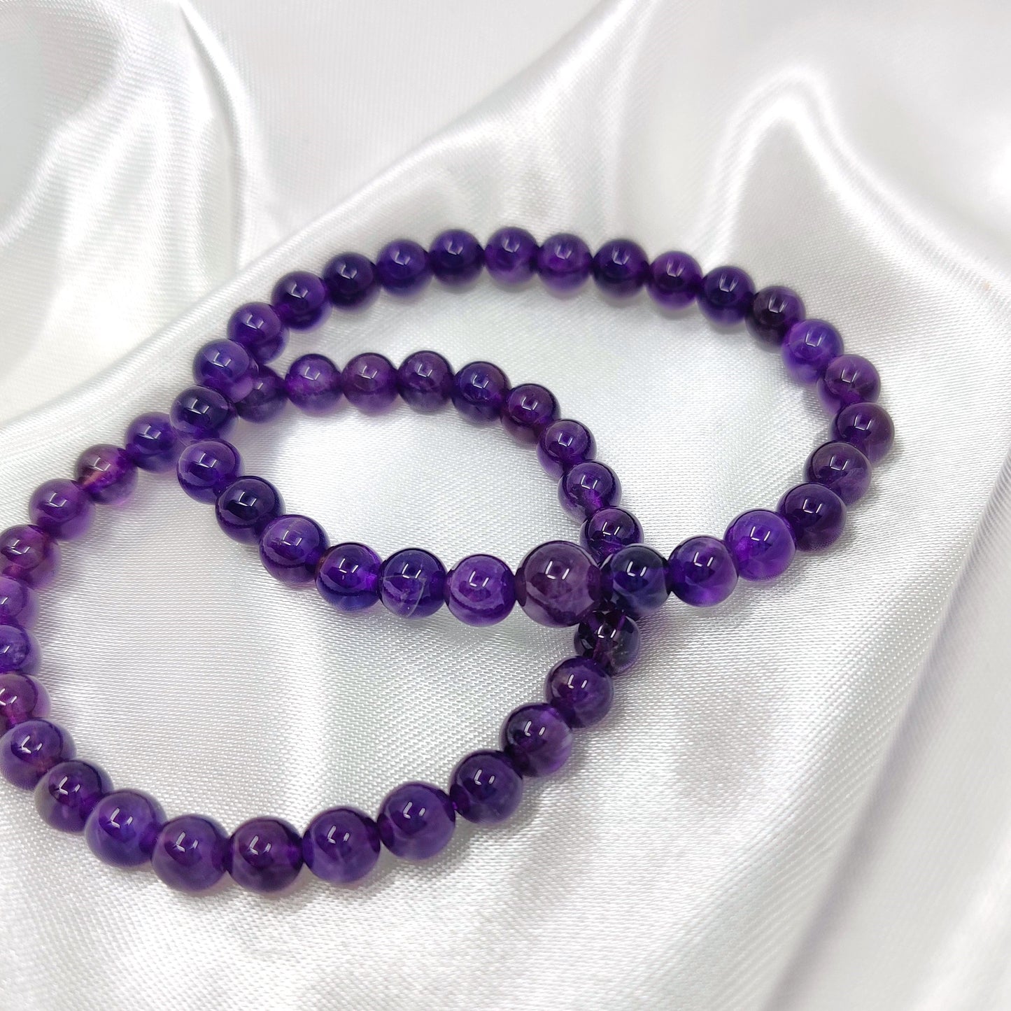 Kirkkaan violetit ametisti helmirannekorut valkoisella kankaalla