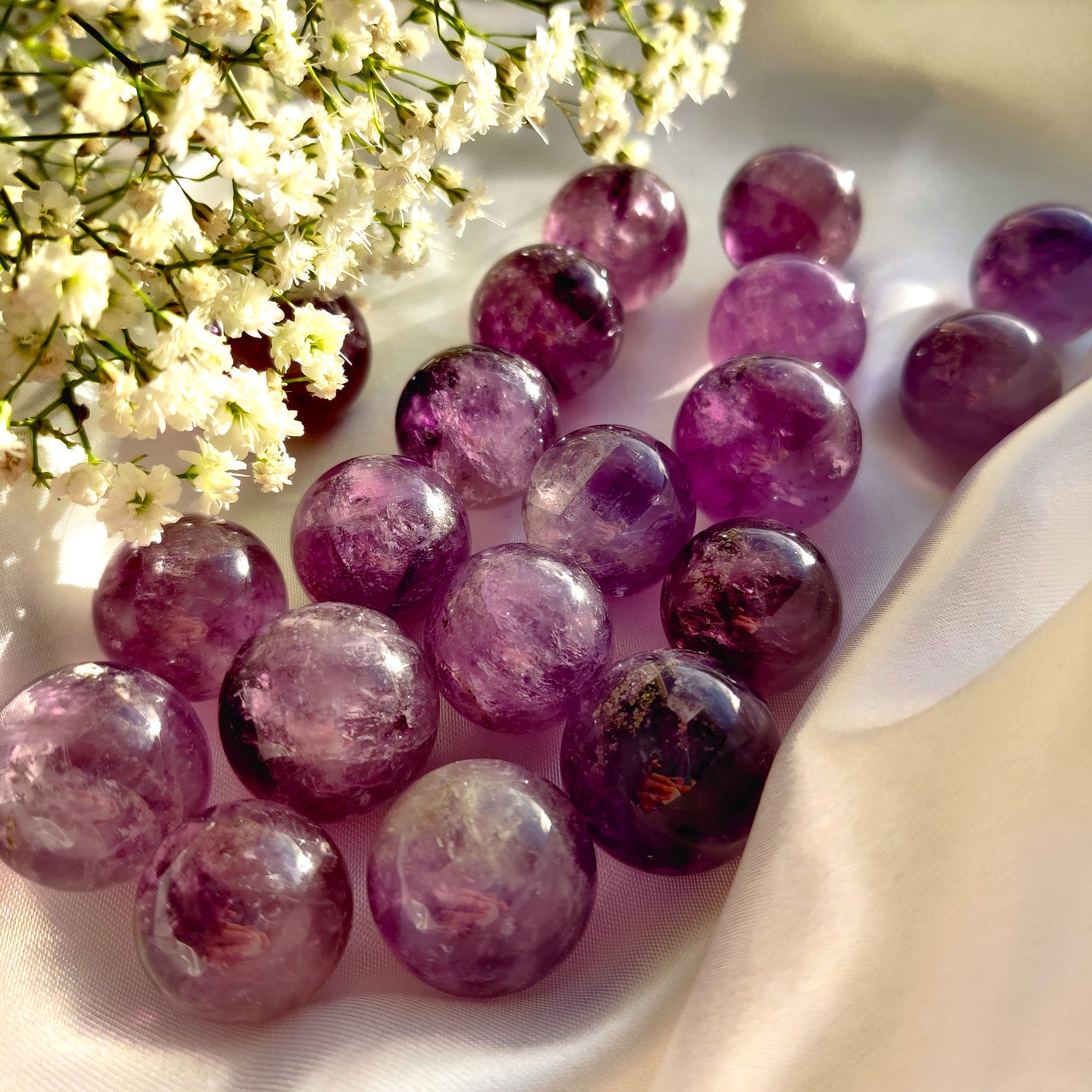 Violetit ametisti kivikuulat valkoisella silkkikankaalla