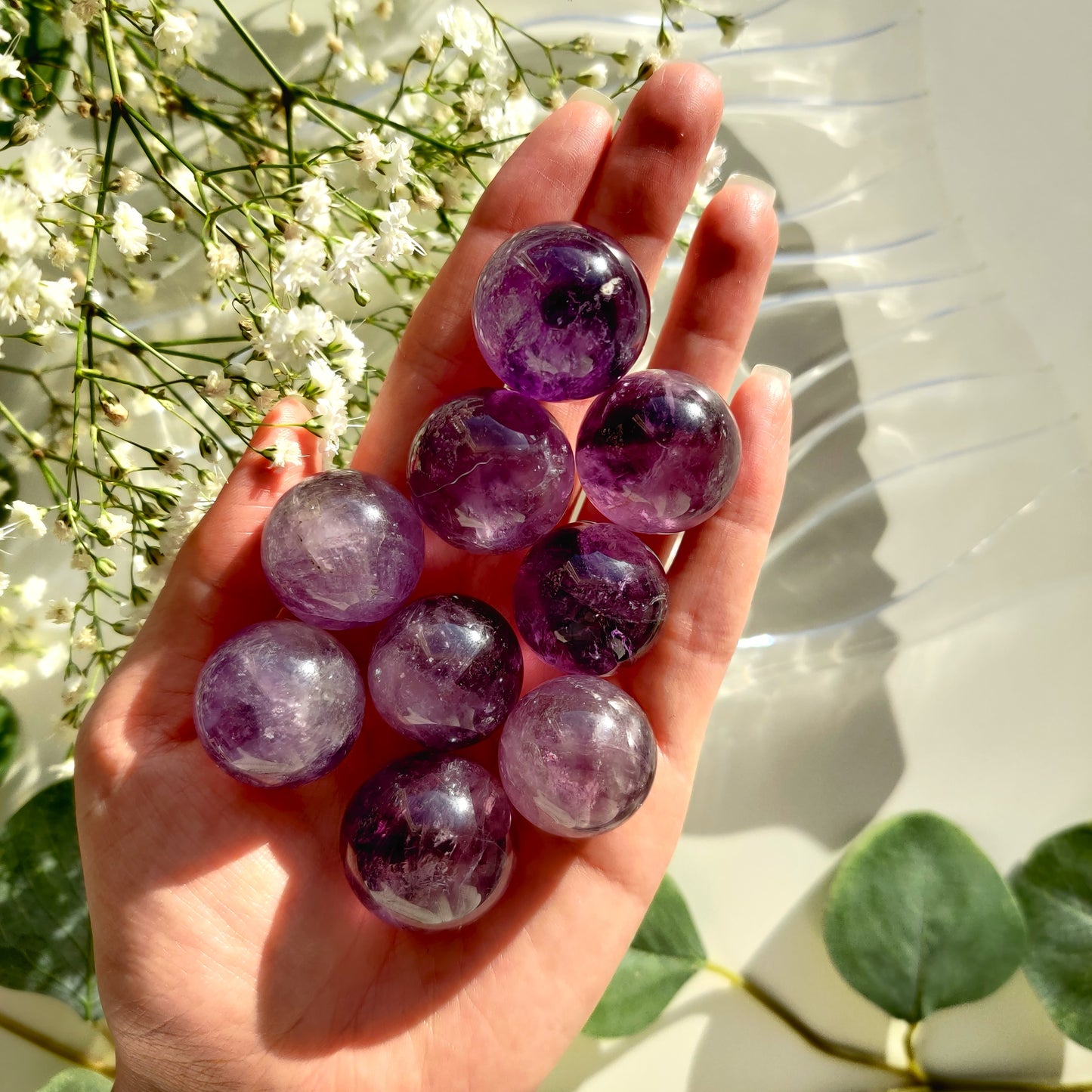 Violetit ametisti kivikuulat kädessä auringonvalossa
