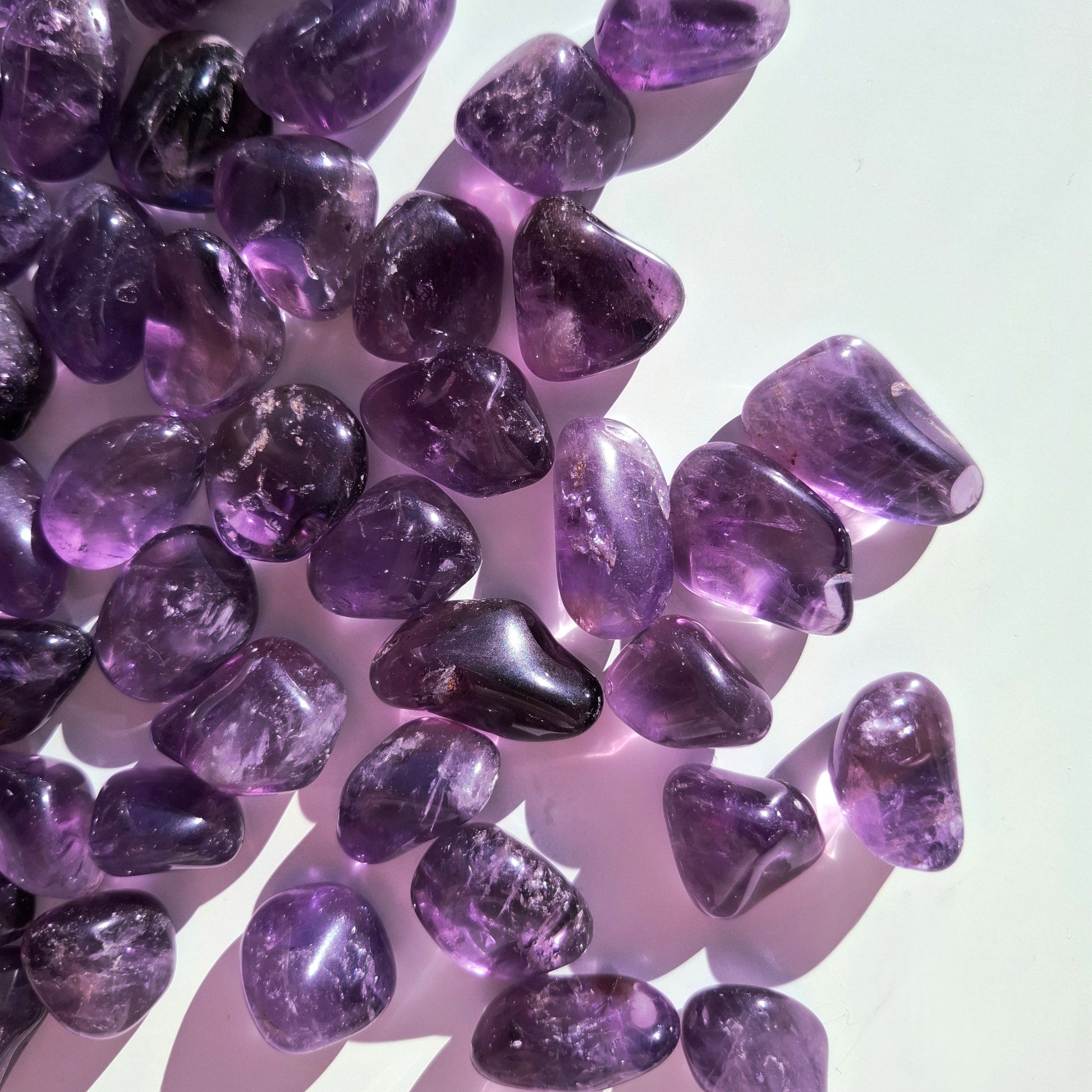 Ametisti rumpuhiottu kivi – violetit luonnonkivet valkoisella taustalla