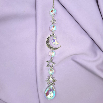 A light-emitting crescent moon sun catcher photographed against a purple background