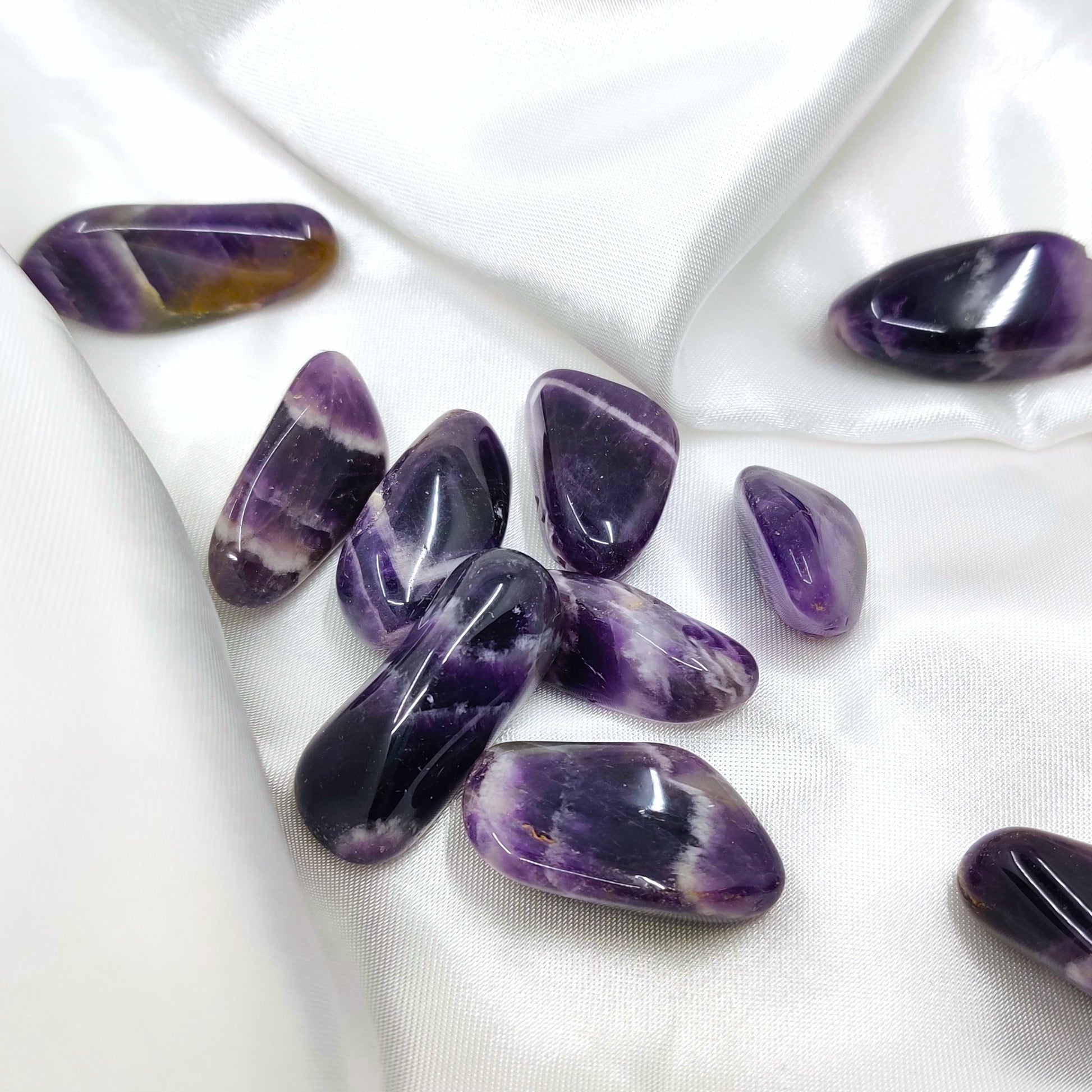 Rumpuhiotut violetin valkoiset chevron ametistit valkoisen silkkikankaan päällä