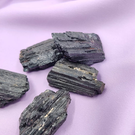 Musta turmaliini raakapalat violetilla silkkikankaalla