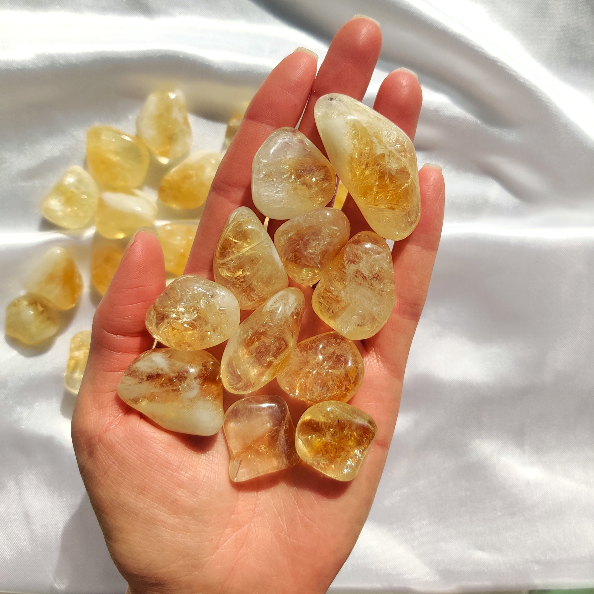 rumpuhiotttuja sitriineijä kädessä ja valkoisella silkkikankaalla