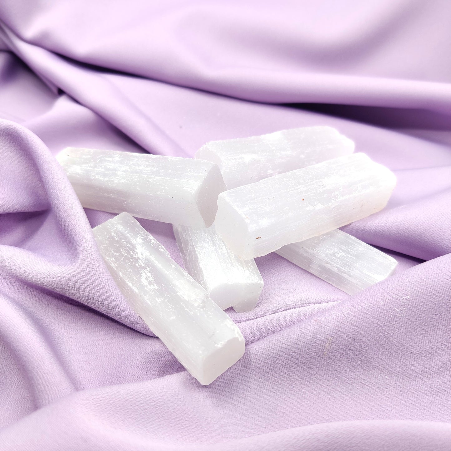 Kirkkaat seleniittisauvat violetilla silkkikankaalla