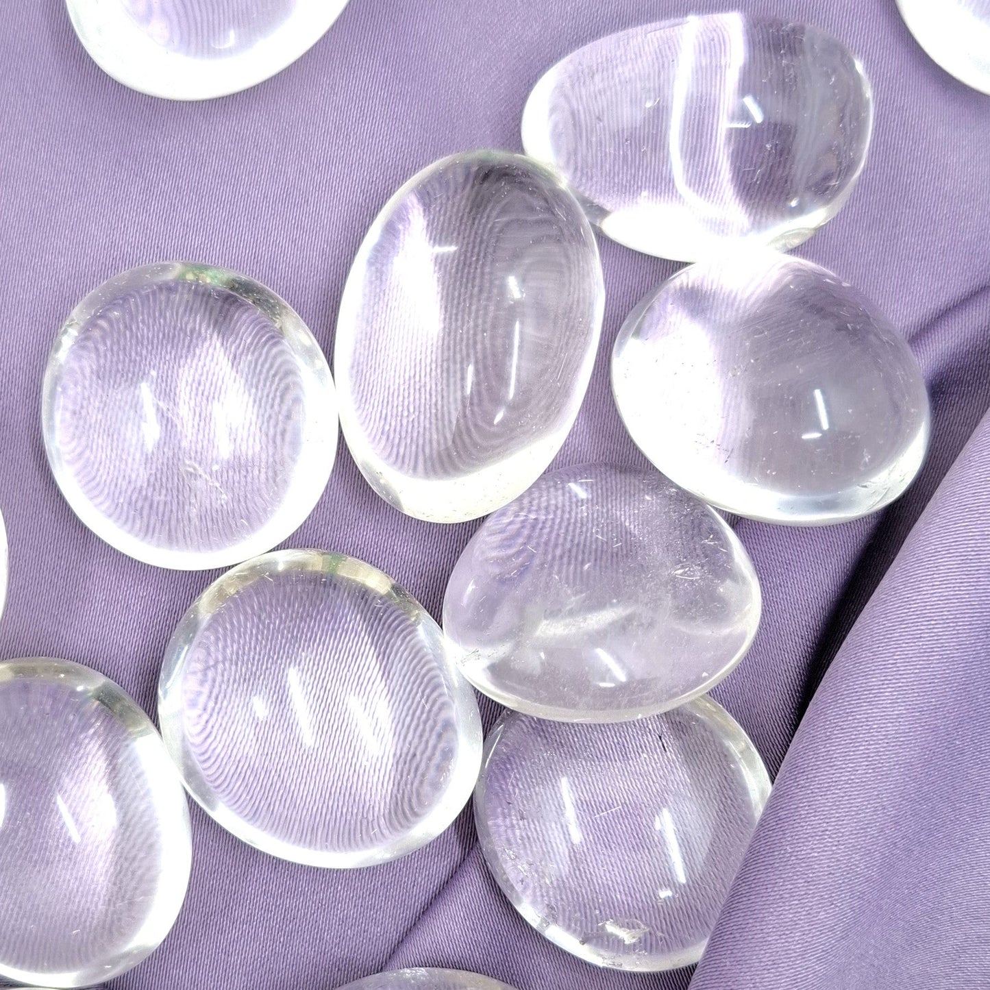 Läpinäkyvät rumpuhiotut vuorikristallit violetilla silkkikankaalla